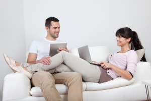 Young couple using laptops in couch